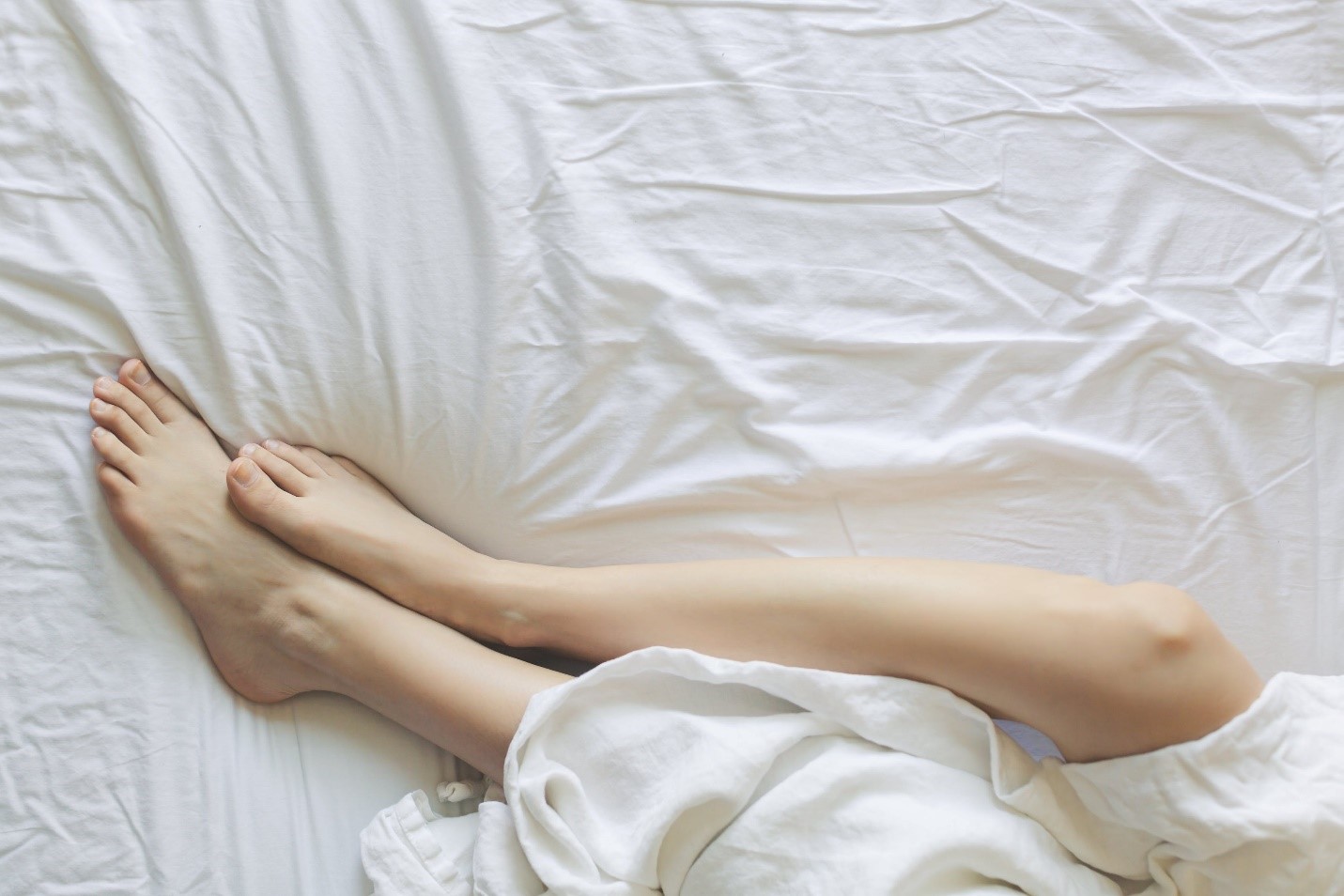 A woman with silky smooth hairless skin lying in bed